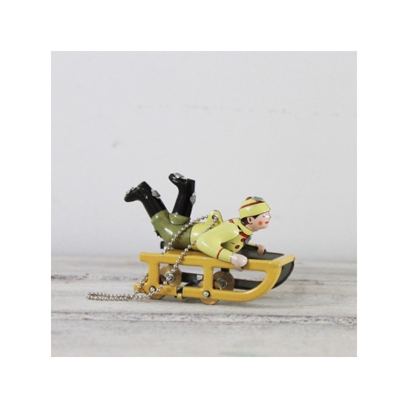 Yellow sled tree ornament with child in winter clothes, yellow sled old toy style, vintage collectible miniature.