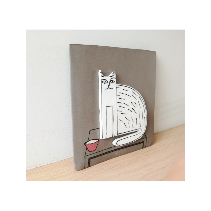 Sitting cat wall hanging, porcelain cat in grey background, square wall tile of stoneware and porcelain, sitting cat art object