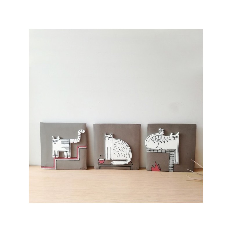 White cat wall hanging, porcelain cat in grey background, square wall tile of stoneware and porcelain, cat on the fireplace