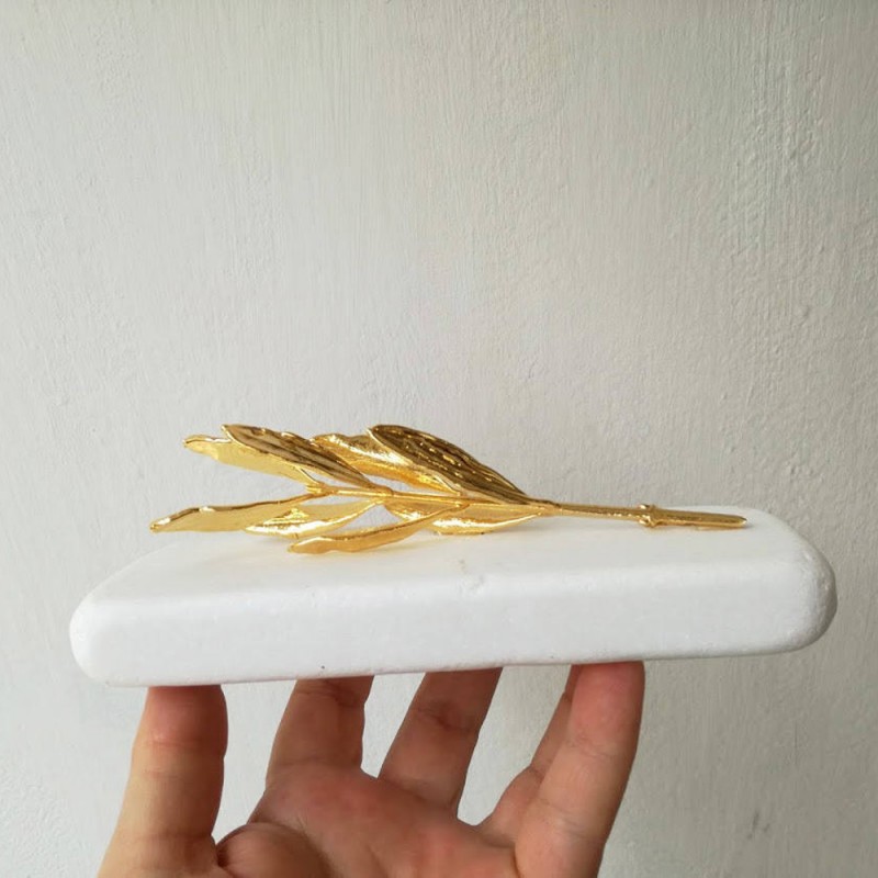 Gold olive branch on white marble, olive twig on white stone, Greek olive gift in gold