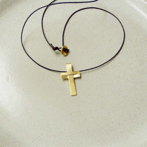 Minimal solid gold cross, modern, unisex, 18 karat gold cross  on a black cord.