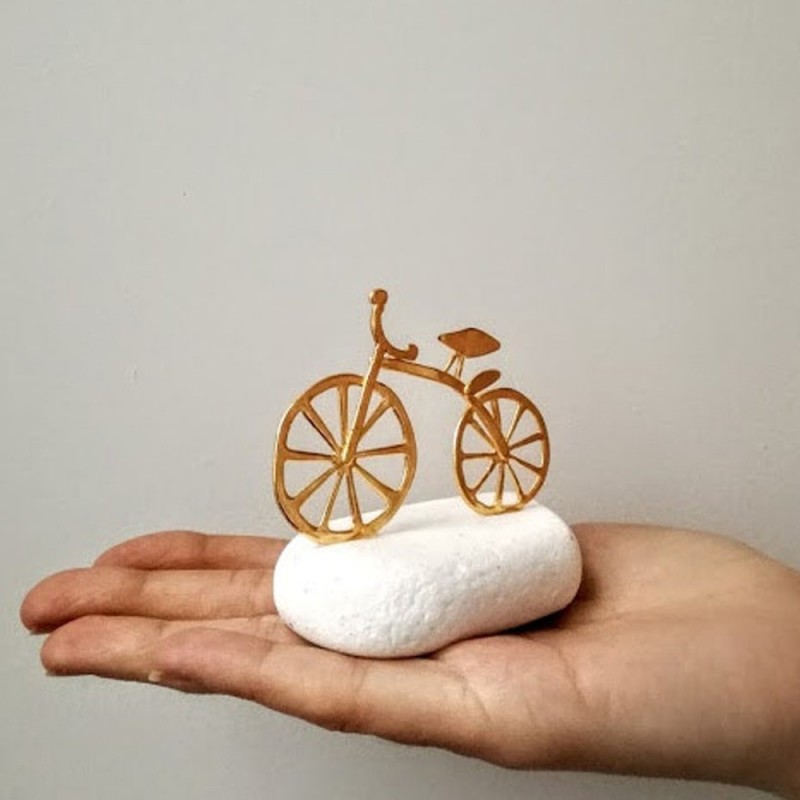 Gold bicycle sculpture, miniature bike sculpture on white stone, gold bike on white stone.