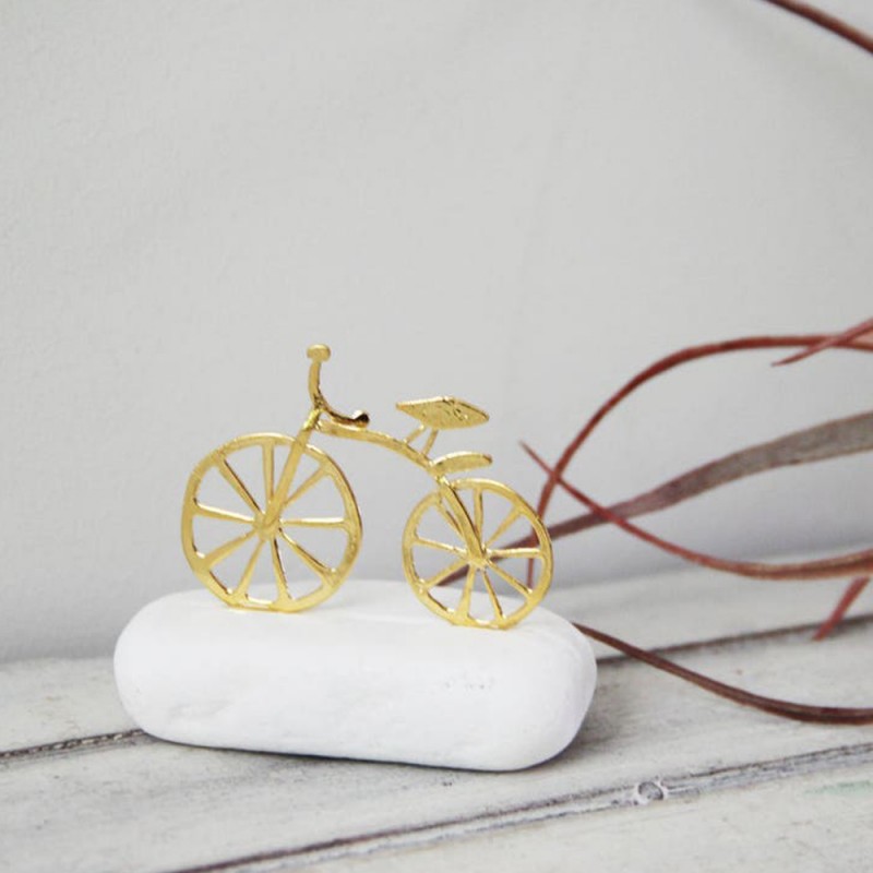 Gold bicycle sculpture, miniature bike sculpture on white stone, gold bike on white stone.