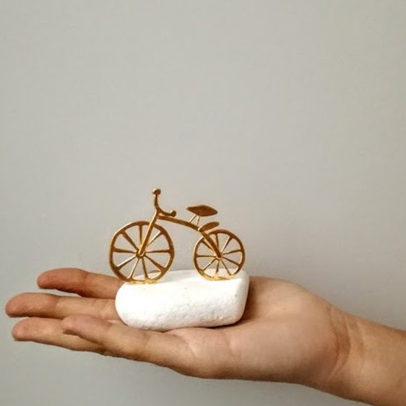 Gold bicycle sculpture, miniature bike sculpture on white stone, gold bike on white stone.