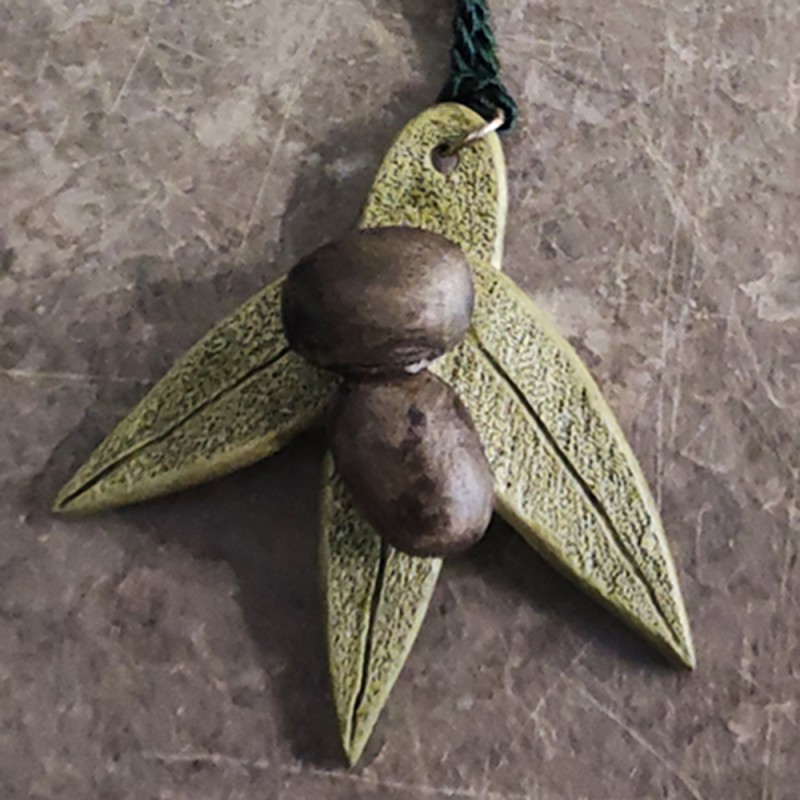 Olive ceramic ornament with ornamental tassel.